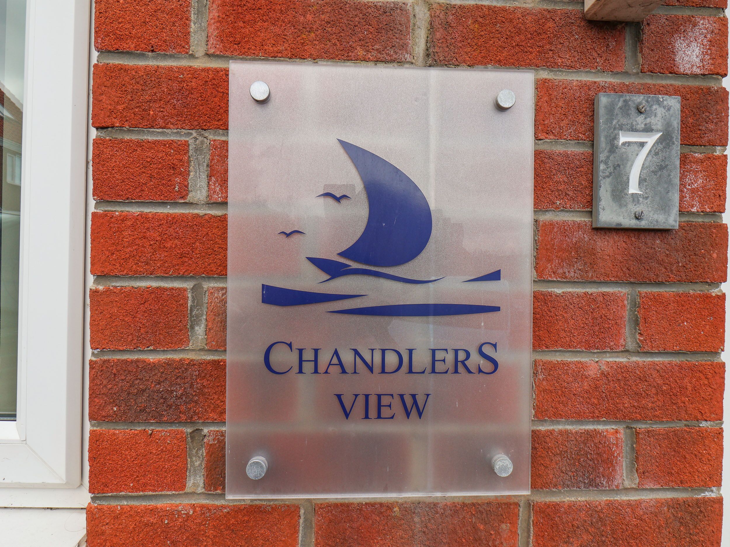 A sign with a sailboat logo and the text "Chandlers View" on a brick wall.