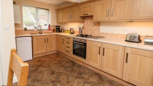 A modern kitchen with wooden cabinets, a dishwasher, a stove, and a toaster. - Chandler's View (Whitby)