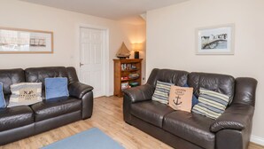 A living room with two dark brown leather sofas, a wooden bookshelf, and a door. - Chandler's View (Whitby)
