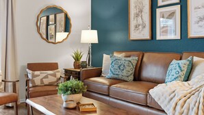 A living room with a brown leather sofa, a wooden coffee table, a lamp, and framed botanical prints on the wall. - 3BR Ozark View Condo | Near Branson Strip (Branson)