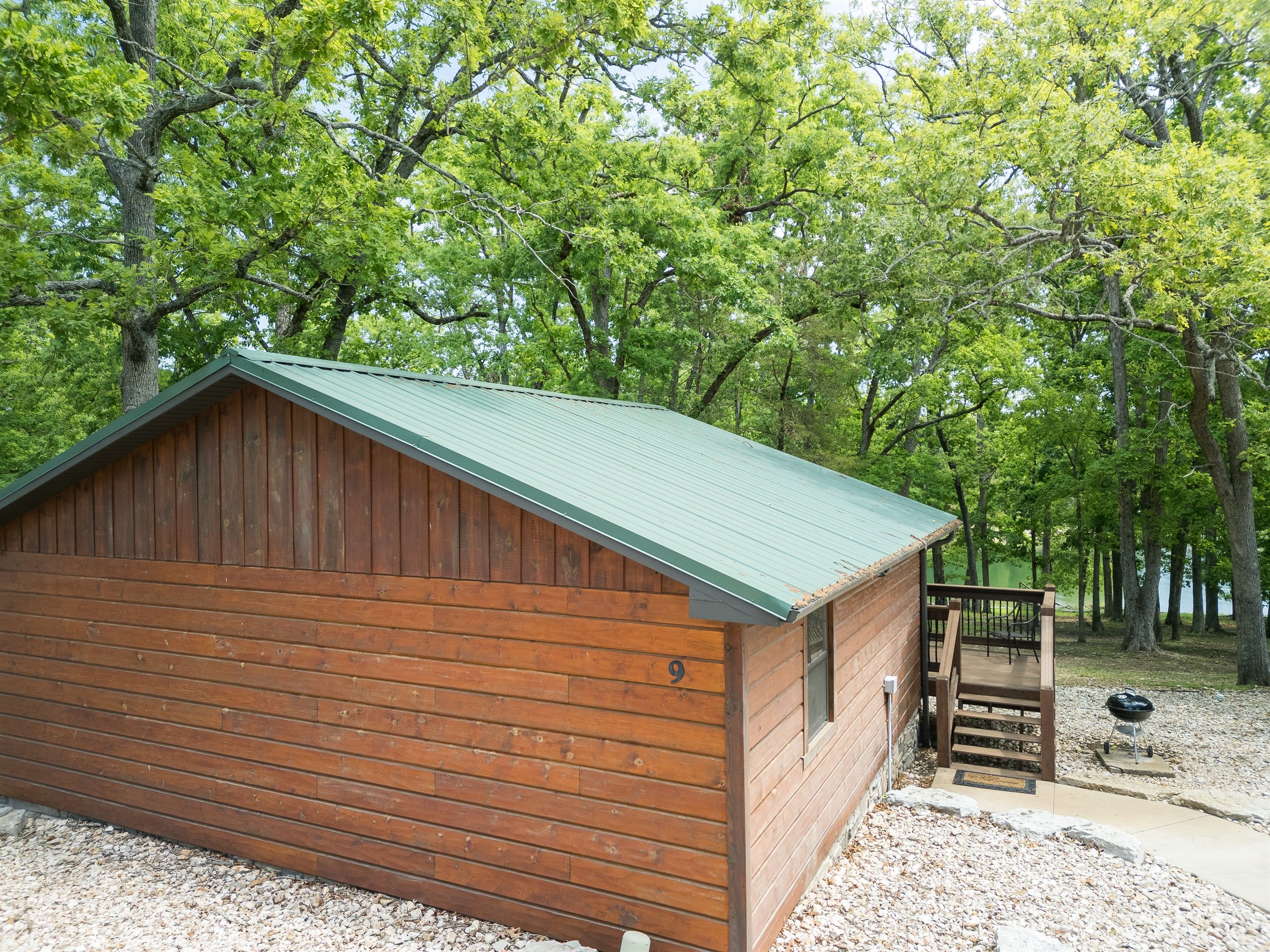 Eine Holzhütte mit einem grünen Dach, umgeben von Bäumen.