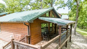 A wooden cabin with a covered porch, a dining area, and a small deck.