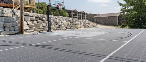 An outdoor basketball court with a stone wall and a wooden deck.