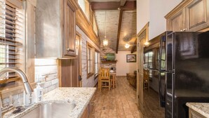 A kitchen with a granite countertop, stainless steel sink, and black refrigerator.