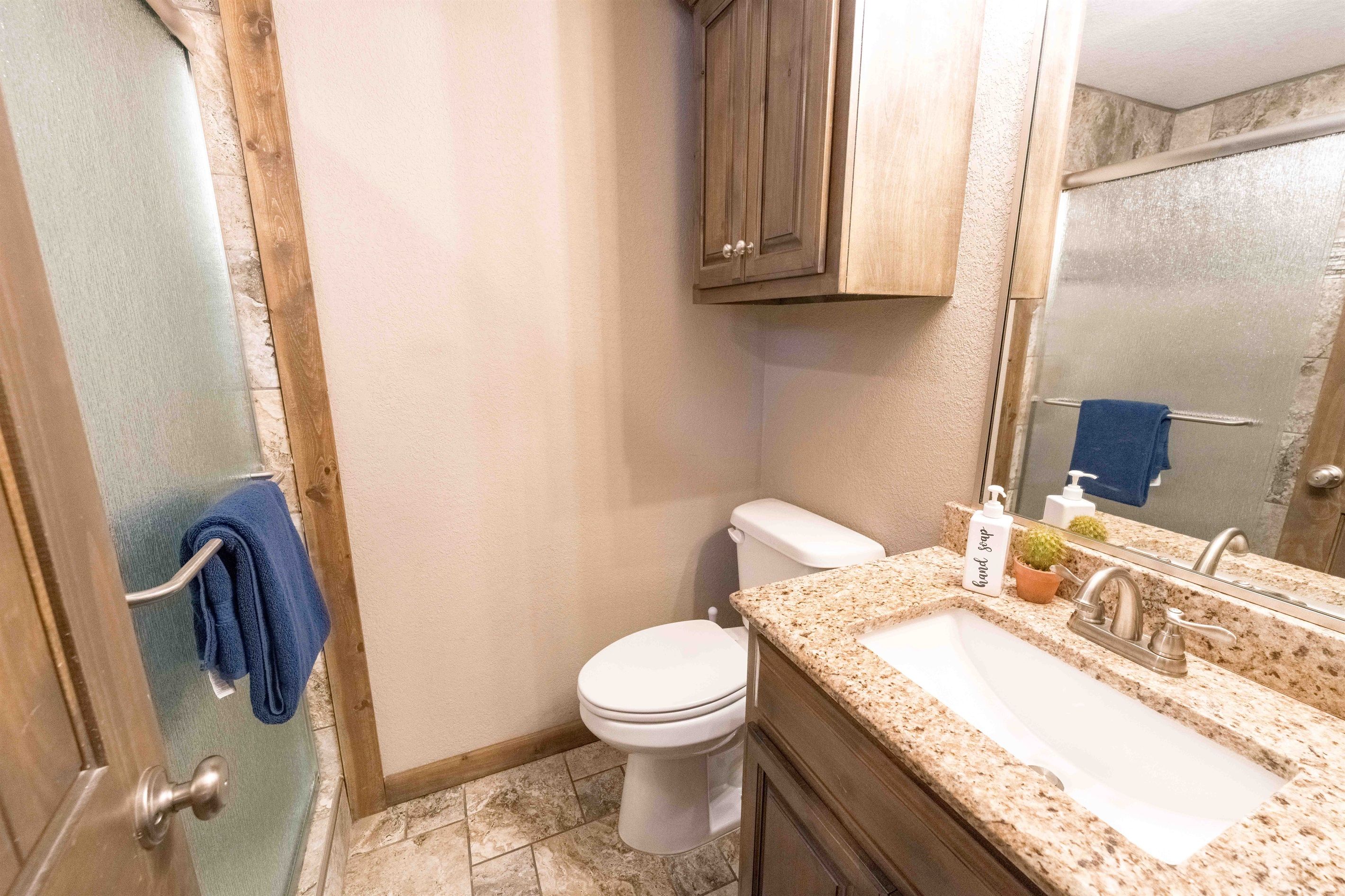 A bathroom with a toilet, sink, and cabinet.