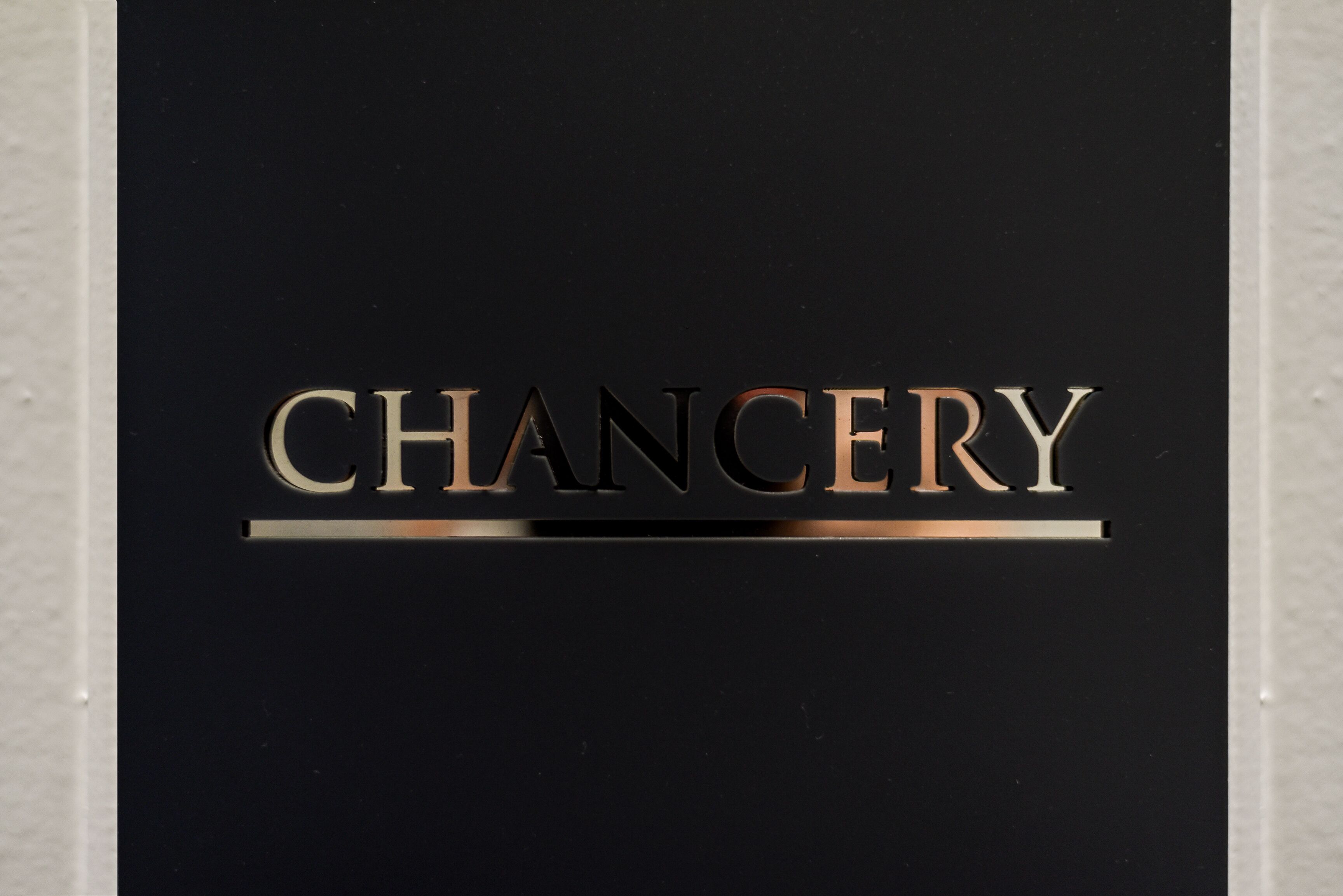 Un panneau noir sur lequel est inscrit le mot « CHANCERY » en lettres métalliques.