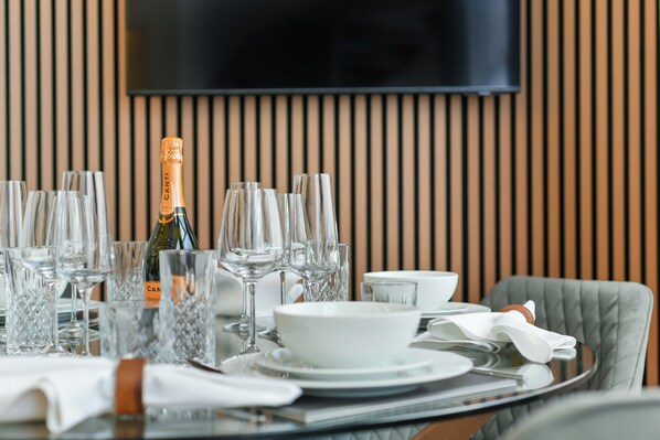 Une table à manger dressée avec plusieurs verres à vin, une bouteille de champagne et un saladier.