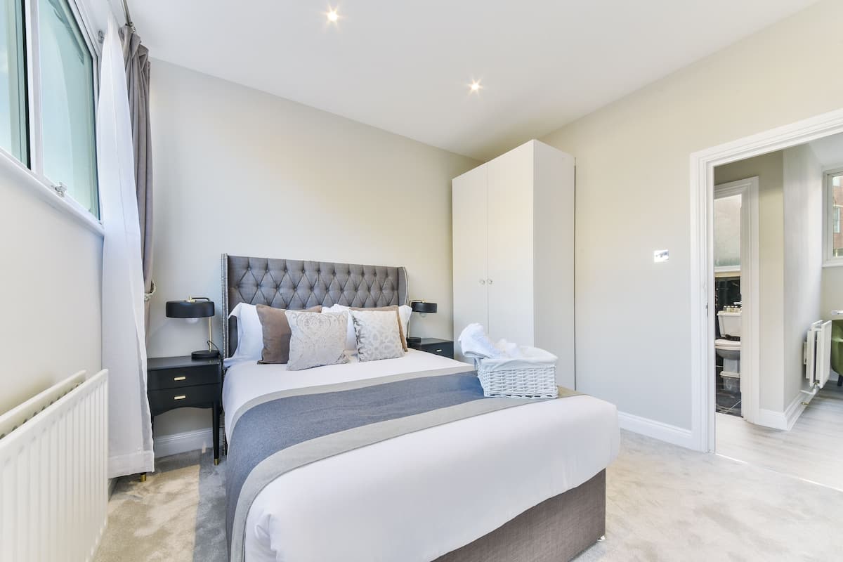 A bedroom with a large bed, bedside tables, a wardrobe, and a bathroom visible through an open door.