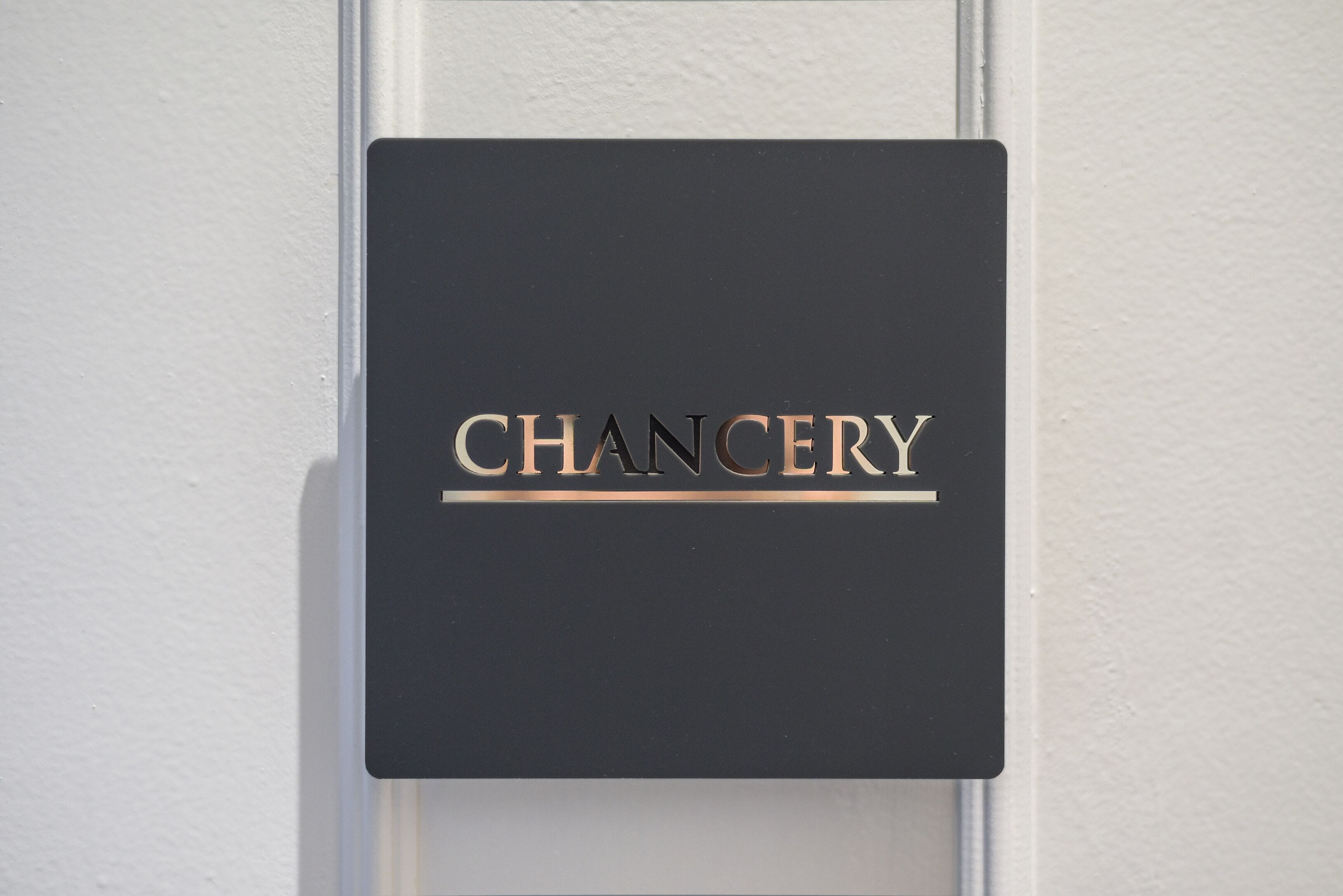 Un letrero negro con la palabra 'CHANCERY' en letras blancas mayúsculas.