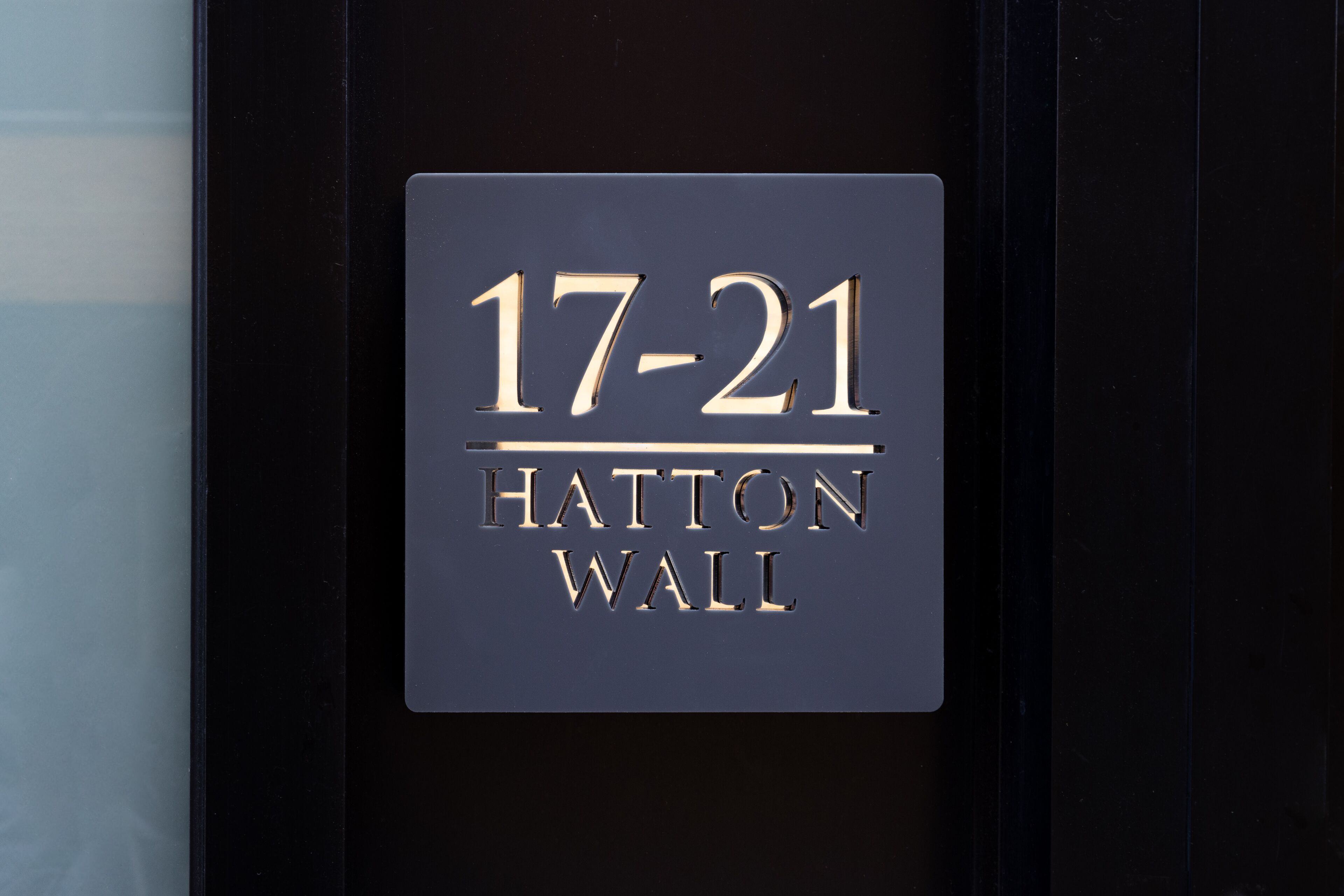Une enseigne avec les chiffres « 17-21 » et les mots « HATTON WALL » sur un fond sombre.