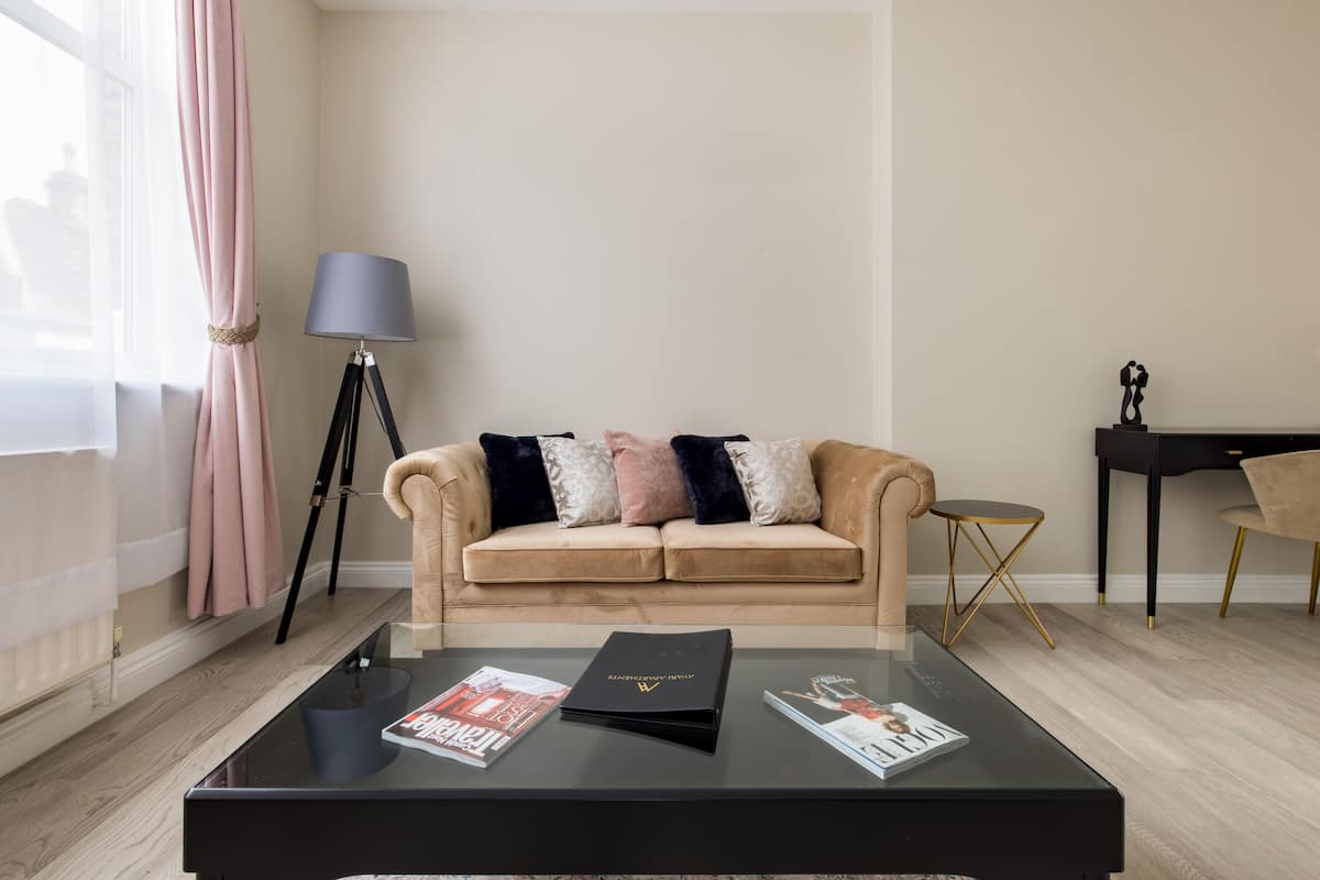 A modern living room with a beige sofa, a glass coffee table, a lamp, and a small side table.