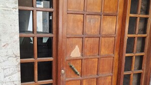 Een houten deur met verschillende glaspanelen en een metalen handgreep.