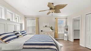 A bedroom with a bed, a ceiling fan, a nightstand, a dresser, and a walk-in closet. - Nautical Lane 146 by Seaside Vacations & Sales (Ocean City)