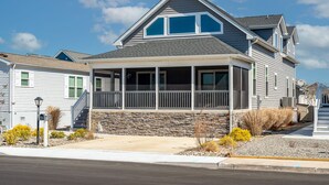 A two-story house with a stone foundation, a covered porch, and a satellite dish. - Nautical Lane 146 by Seaside Vacations & Sales (Ocean City)