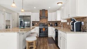 A modern kitchen with white cabinets, a stainless steel refrigerator, a black stove, and a coffee maker. - Nautical Lane 146 by Seaside Vacations & Sales (Ocean City)