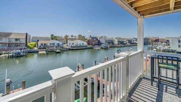 A waterfront view from a balcony with a wooden ceiling, a marina with boats, and residential buildings in the background. - Newport Bay 5 by Seaside Vacations & Sales (Ocean City)