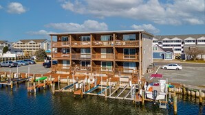 A multi-story wooden building with balconies, located near a marina with docked boats. - Newport Bay 5 by Seaside Vacations & Sales (Ocean City)