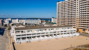 Un hôtel situé en bord de mer, doté de nombreux balcons, d’une plage de sable et offrant une vue sur l’océan.