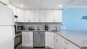A modern kitchen with white cabinets, stainless steel appliances, and a grey countertop.