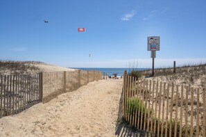 A sandy beach path with wooden fences on both sides, leading to the ocean. - Siesta Villa 103S by Seaside Vacations & Sales (Ocean City)