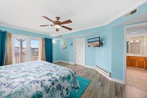 A bedroom with a bed, a ceiling fan, a TV, and a view of the outside. - Somerset on 2nd 202 by Seaside Vacations & Sales (Ocean City)
