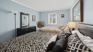 Une chambre à coucher avec un lit, une commode et un grand miroir.