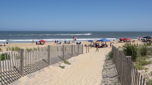 Una playa arenosa con una valla de madera y sombrillas.