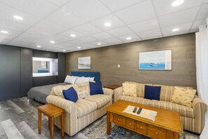Quarto moderno com cama, dois sofás listrados, uma mesa de centro de madeira e obras de arte nas paredes.