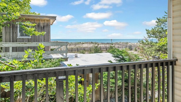 Una terraza de madera con vista a la playa y al océano.