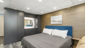 Un dormitorio moderno con una cama grande, armario empotrado, espejo y un cuadro en la pared.