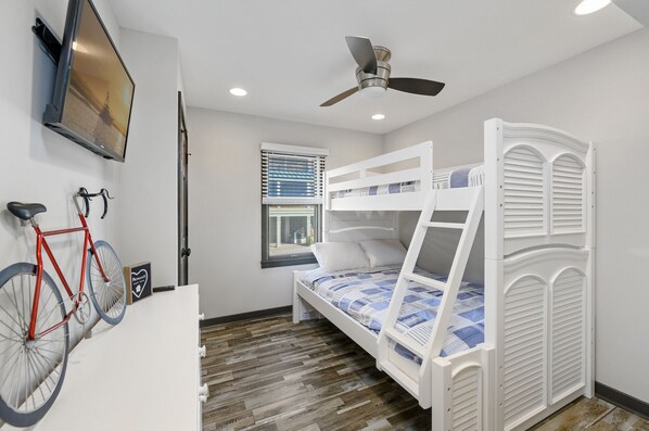 A bedroom with a bunk bed, a bicycle, a ceiling fan, and a window with blinds.