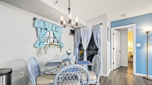A dining area with a glass-top table, wicker chairs, and a chandelier.
