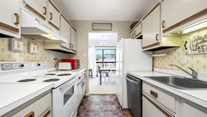 Una cocina compacta con armarios blancos, un tostador rojo y suelo de baldosas.