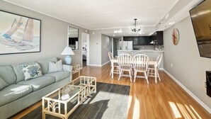 A modern living room with a sofa, coffee table, and dining area with chairs and a table.