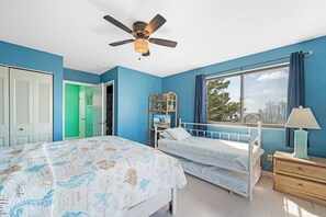 Camera da letto con due letti, una ventola a soffitto, una finestra con vista e un comò.