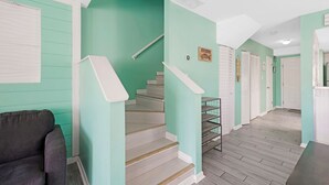 Eine Treppe mit Handlauf, ein dunkelgraues Sofa und ein Holzboden.