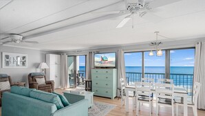 A spacious living room with a sofa, chairs, a dining table, and a TV displaying 'Seaside Vacations Kays'. - Summer Beach 501 by Seaside Vacations & Sales (Ocean City)