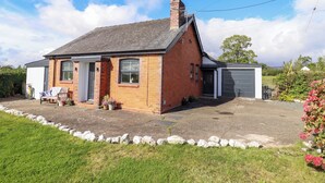 A single-story brick house with a grey roof, a chimney, and a garage. - Bethania (Oswestry)
