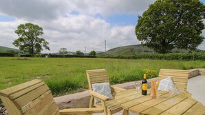 A wooden outdoor seating area with a table, chairs, and a bottle of wine. - Bethania (Oswestry)