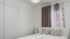 A bedroom with a bed, pillows, a nightstand, a wardrobe, and curtains. - Apartamento Adeje con Piscina (Adeje)