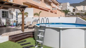 A residential building with a swimming pool, outdoor furniture, and a ladder leading to the pool. - Apartamento Adeje con Piscina (Adeje)
