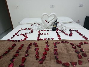 A bed with rose petals arranged in a heart shape and a bottle of perfume on it. - Casa Porto do Amor (Ipojuca)