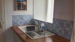 Una cocina compacta con encimera de madera, un lavamanos y un salpicadero de azulejos.