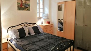 Une chambre à coucher avec un lit, une commode, une armoire, une fenêtre et un tableau au mur.
