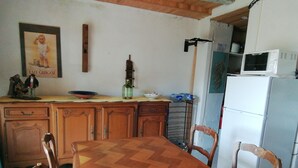 Une cuisine avec des meubles de rangement en bois, une table à manger en bois et des chaises. On y trouve également un four à micro-ondes et un réfrigérateur.