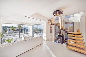 Relax in a spacious area with a panoramic view of the surrounding landscape, featuring a contemporary staircase and a cozy seating area.