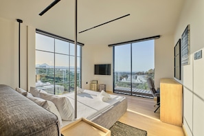 Enjoy a panoramic view of the surrounding landscape from the comfort of this stylish room, featuring a large bed and a flat-screen TV.
