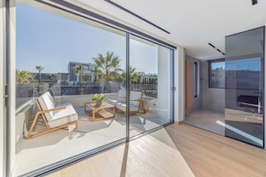Relax on the spacious balcony with a clear view of the surrounding landscape, featuring a glass door leading to a living space and comfortable seating options.