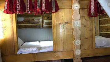 A wooden cabin with two beds, each with white linens.