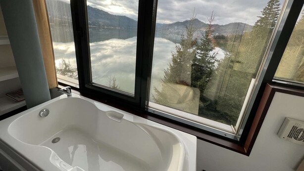 Un baño con bañera y un amplio ventanal con vistas a un paisaje montañoso.